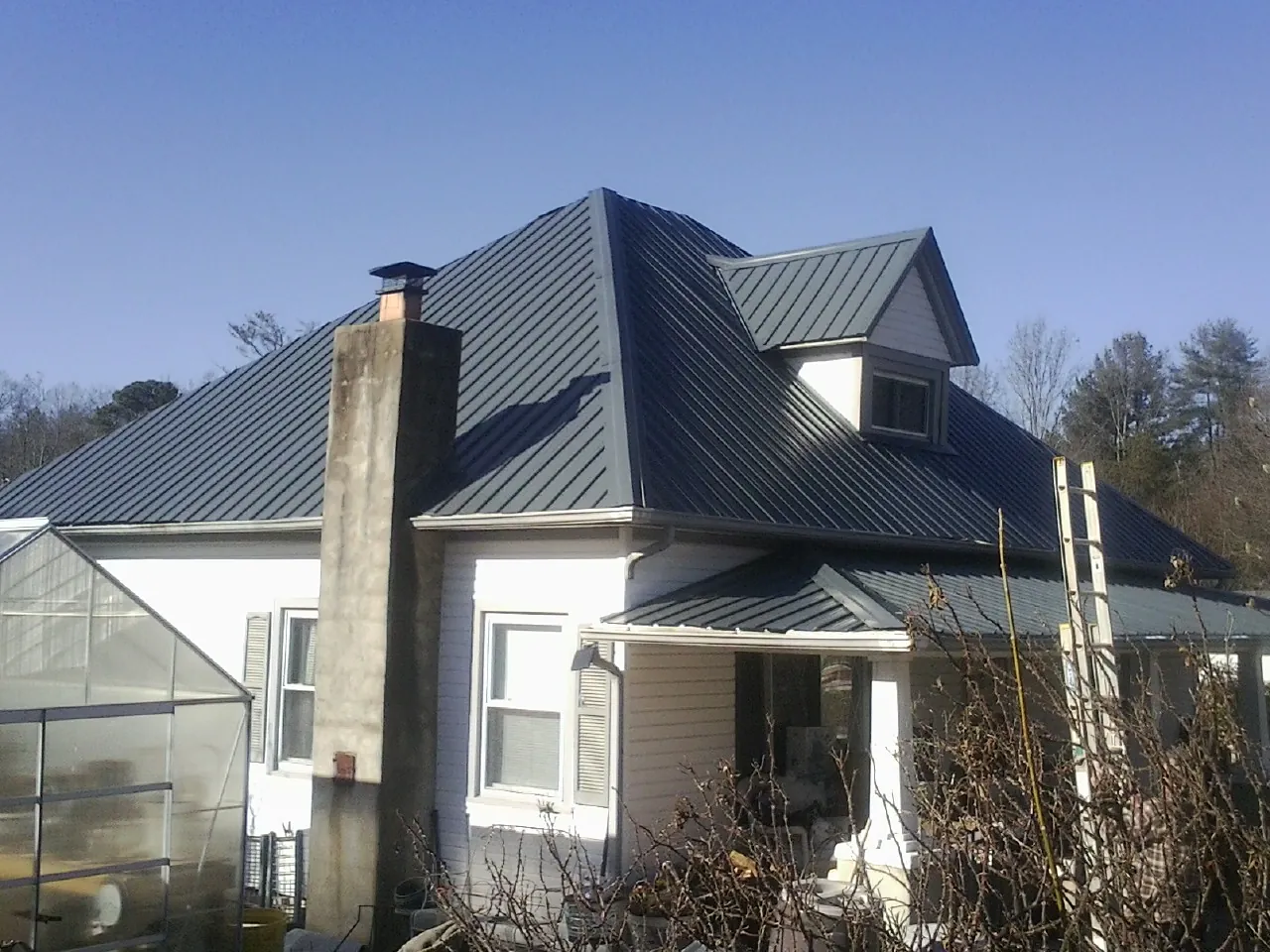 Dark blue standing seam metal roof on a white farmhouse with dormer — Slate & Tile Roof Repair by Roofing Brothers in Sugarcreek