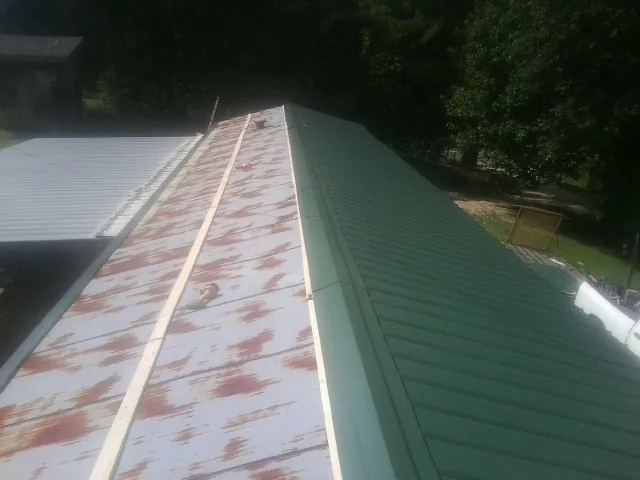 Old rusted panels beside newly installed green metal roofing — Wind Damage Roof Repair by Roofing Brothers in Sugarcreek