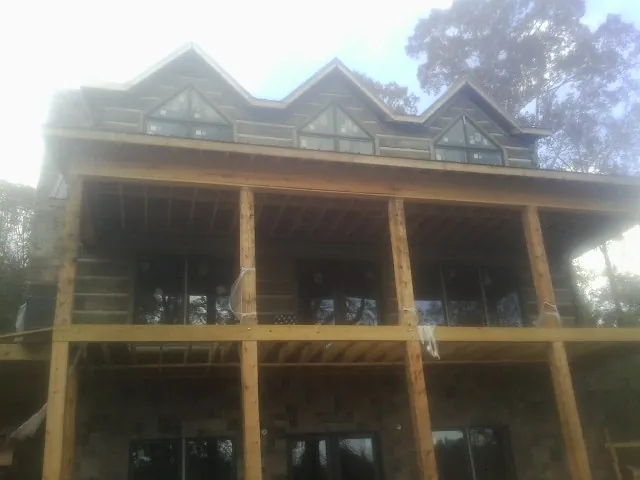 Dormers and porch framing on a large log home under construction — Roof Coating work by our crew in Sugarcreek