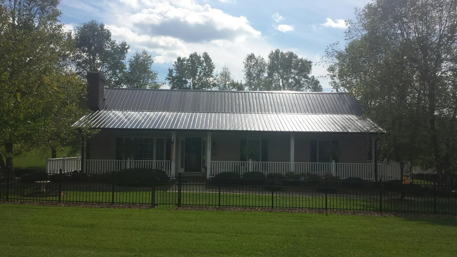 Gray metal roof on a brick ranch with a full width front porch — Gutter Guard Installation work by our crew in Sugarcreek