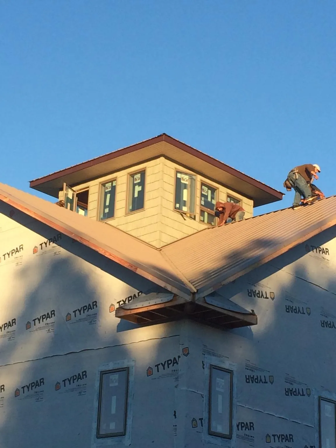 Roofers working around a rooftop cupola on a new metal roof at sunset — Roof Waterproofing in Sugarcreek by Roofing Brothers